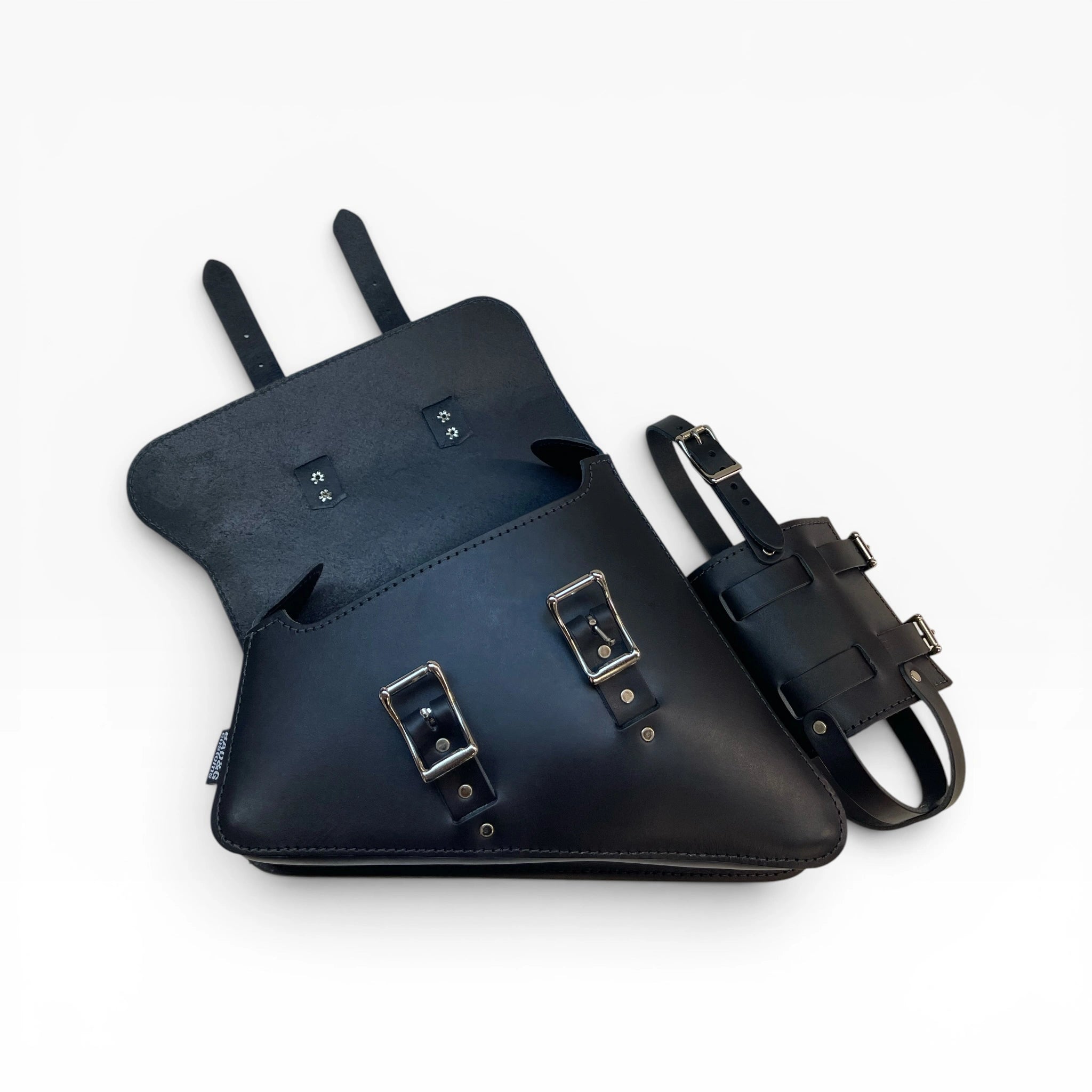 A black leather saddle bag with silver buckle hardware, shown open with its strap and buckle closure detail displayed alongside on a clean white background.